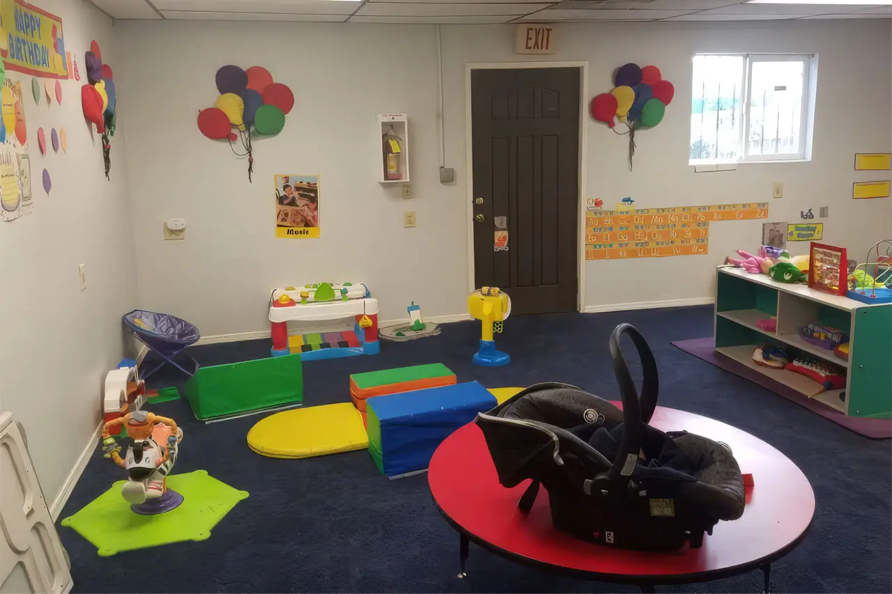 A colorful playroom filled with various toys and a baby car seat in the corner, creating a safe play environment.